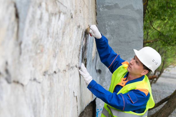 a worker in a helmet cleans vandal inscriptions from the walls in the city